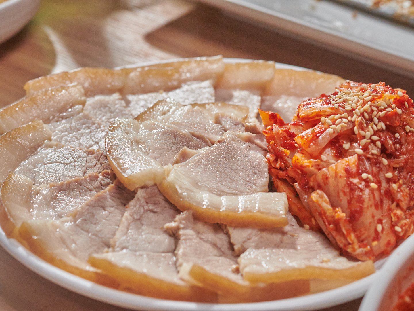 성심조림 제주공항점 겉절이 수육 — 흰 접시에 편으로 썬 수육과 깨를 뿌린 겉절이.